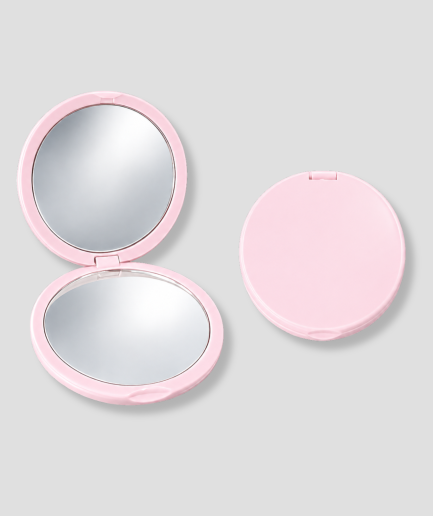 Espejo de maquillaje compacto de color rosa, con imágenes de él abierto y cerrado sobre un fondo gris claro